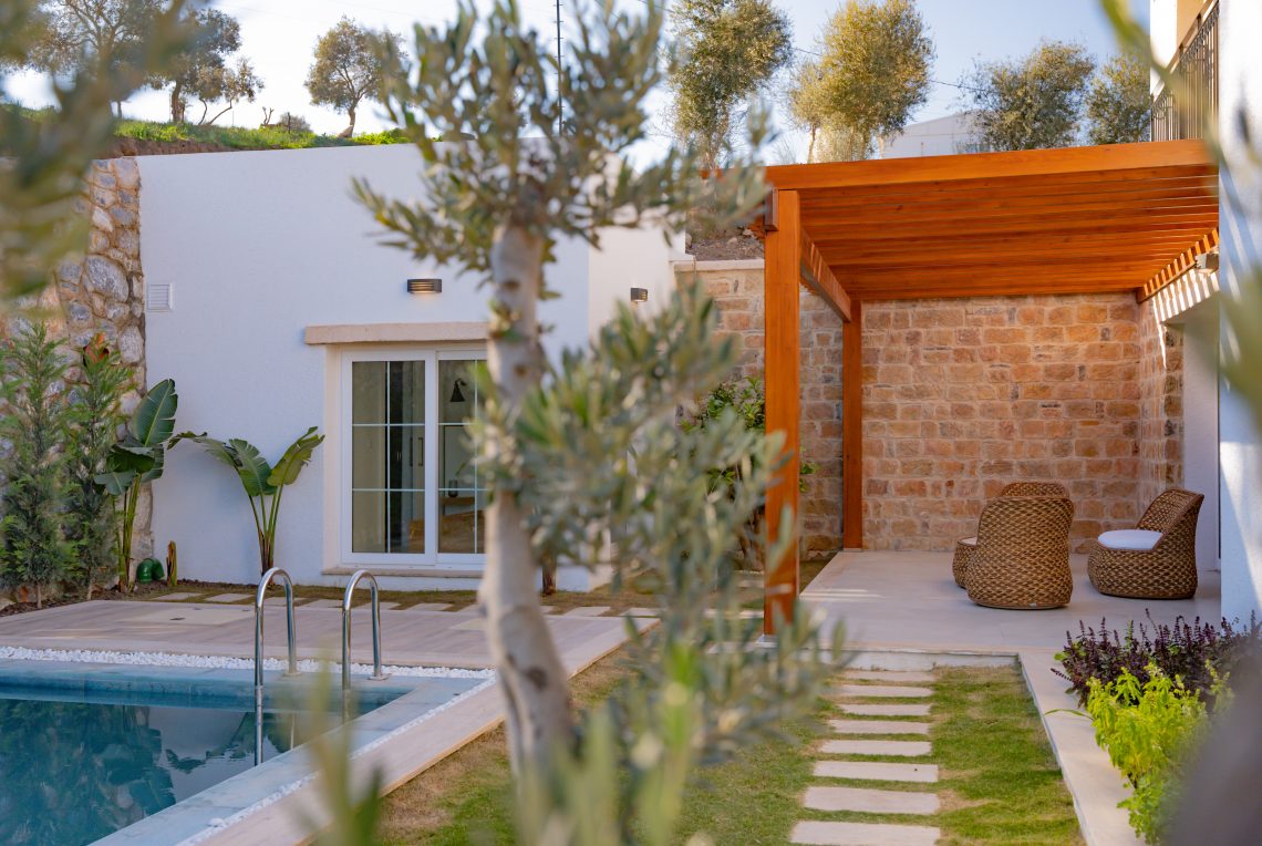 Stone garden path leading to a swimming pool surrounded by lush greenery